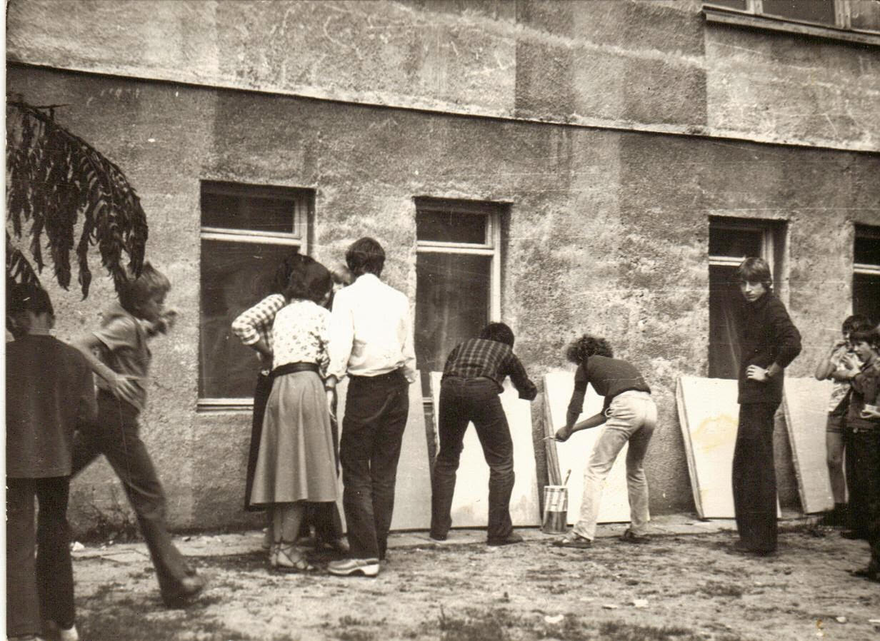 Renata taking a picture of other students priming canvasses or making art often outdoors at her art school.